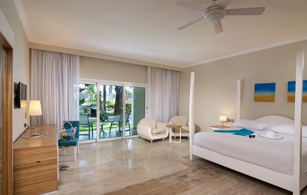 Bright Junior Suite with a four-poster bed, armchairs and sliding glass doors to the terrace
