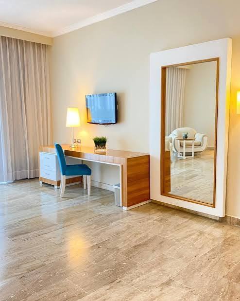 Junior Suite desk area with a wall-mounted television, blue chair and full-length standing mirror
